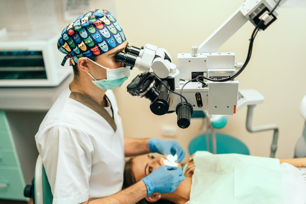 Dentist examine oral cavity of female patient with microscope