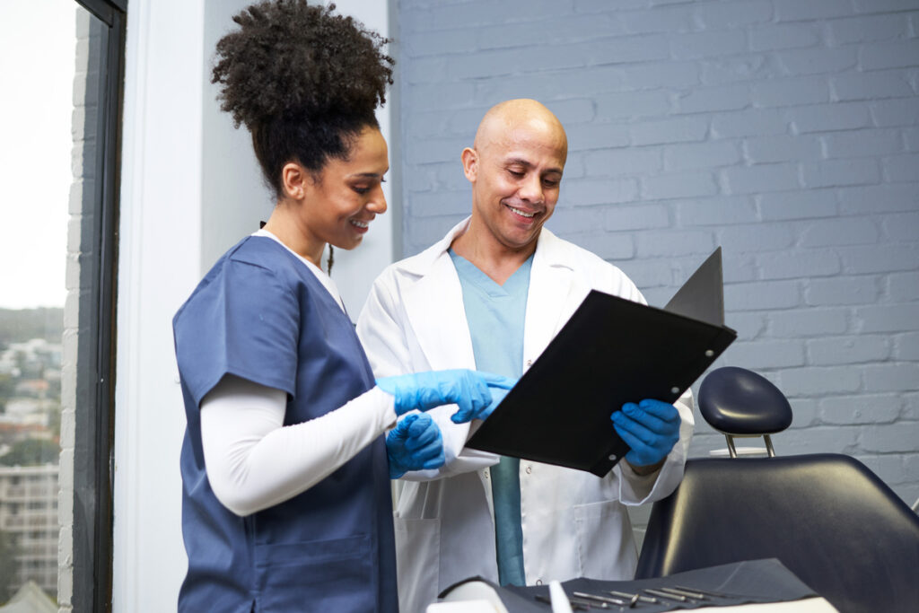 Smiling Healthcare Professionals Reviewing Patient Records in a Modern Dental Office