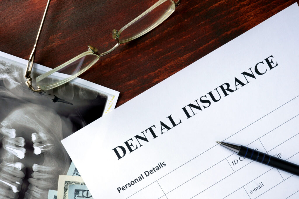 Dental insurance form on a wooden table, with a mouth X-ray scan beneath it.