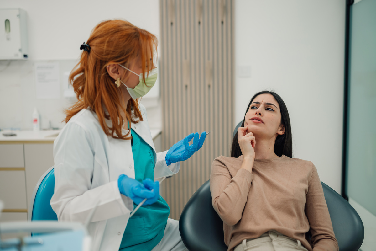 Dentist explaining treatment to patient having toothache in dental clinic